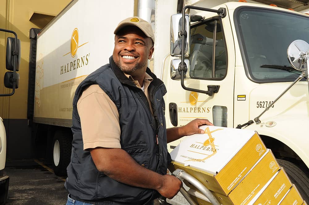 Bottom-employ-opt-1 (1) Picture of a Halperns' delivery driver unloading cases of steak & seafood products off the delivery truck.