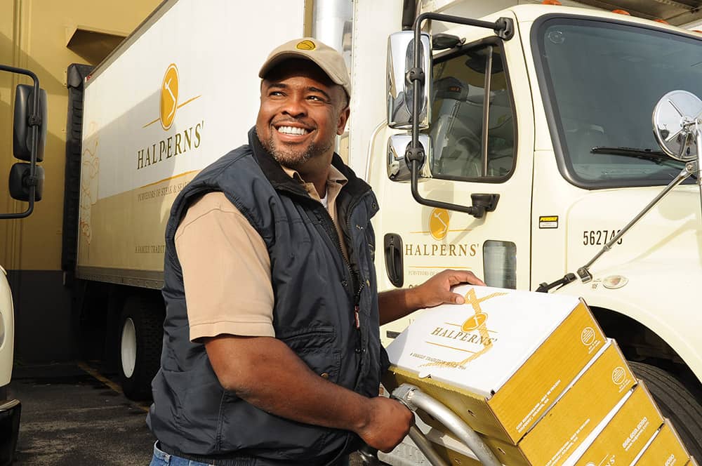 Picture of a Halperns' delivery driver unloading cases of steak & seafood products off the delivery truck.